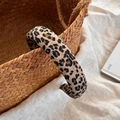 Close-up of a wide leopard print headband resting on a woven basket with beige linen - Wide Leopard Print Headband