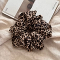 Detailed view of leopard print oversized scrunchie on beige linen fabric texture - Leopard Scrunchie