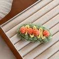 Détail de la pince à cheveux crochetée avec pompons orange et perles blanches sur laine - Balle Orange Vert