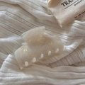 Détail d'une pince à cheveux en acétate marbré sur un fond en tissu blanc - Beige