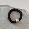 Detail of dark brown pleated satin hair scrunchie with a silver metal ball accent - Brown