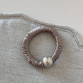 Detail of elegant champagne satin hair tie with pleated texture and silver metallic bead - Beige