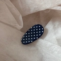 Primo piano di un fermaglio per capelli blu navy a pois bianchi su carta ruvida - Clip Becco d'Anatra Ovale a Pois - Blu Marino