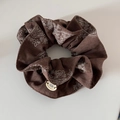 Detail of vintage paisley scrunchie with BOTANI logo tag on a textured brown fabric - Coffee Cinched Style
