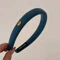 Macro view of textured teal headband with gold Korea tag and hand made woven label - Blue