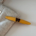 Dettaglio di fermaglio giallo con fiocco marrone su bordo di borsa di tela minimalista - Base Gialla Fiocco Marrone - Foglia di Salice