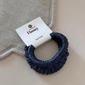 Detail of a dark blue satin scrunchie with a handmade tag on a minimalist surface - Navy Blue