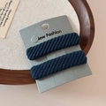 Detailed view of two dark blue twill knit hair scrunchies on a minimalist display card - Blue