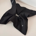 Macro shot of striped fabric scrunchie with handmade tag and heart-shaped metal charm - Striped Scarf Scrunchie - Black