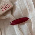 Detail of handmade burgundy acetate hair clip with gold label on linen background - Gold Label Acetate Oval Clip / Red