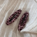 Dettaglio di due fermagli per capelli viola leopardati su sfondo di tessuto testurizzato - Leopardo Rosa Ovale