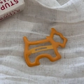 Nahaufnahme einer leuchtend orangefarbenen Haarspange in Hundeform auf weißem Stoff - Hohler Hund BB-Gelb
