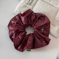 Detailopname van een bordeauxrode imitatielederen haarelastiek met een mode-etiket - Rood