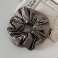Detail van zilveren metallic scrunchie met slangenleer textuur en mode label erop - Bruin