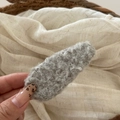Close-up of a soft grey plush fleece hair clip with warm autumn texture and oval design - Gray