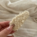 Nahaufnahme einer beigen Lammwoll-Haarspange mit dicker, lockiger Plüschtextur und Details - Cremeweiß