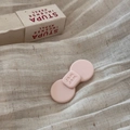 Detailansicht einer rosa Schleifen-Haarklammer auf weichem, beigem Leinenhintergrund - Buchstaben Kleine Schleife / Rosa