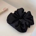 Detailed texture of a large black fabric scrunchie with soft pleats on a neutral surface - Black