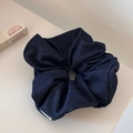 Detailed texture of a large denim blue scrunchie with a white woven brand label - Navy Blue