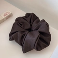 Close-up of deep brown fabric scrunchie with textured twill weave on a minimalist surface - Coffee