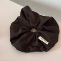 Close-up of dark brown corduroy scrunchie texture with a white handmade fabric label - Dark Brown