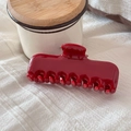 Close-up of a large glossy dark red hair claw clip on white textured fabric background - Red