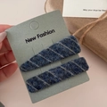 Detailed view of two blue and grey plaid knit hair clips on a New Fashion display card - Blue
