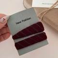 Detail of burgundy knitted BB hair clips with gray twill pattern in hand - Red