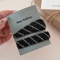 Close-up of knit fabric hair clips in grey and white stripes on a fashion display card - Black