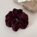 Dettaglio di un elastico per capelli in maglia bordeaux a righe con texture morbida - Rosso