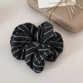 Close-up of black and white striped knitted scrunchie with warm texture and gift packaging - Black