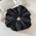 Gros plan d'un grand chouchou noir à pois blancs en maille douce pour cheveux - Noir