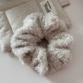 Makroaufnahme eines weichen, cremeweißen Plüsch-Haargummis mit flauschiger Kunstpelz-Textur - Beige