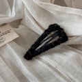 Close-up of black knitted wool hair clip with colorful speckled texture on linen - Black