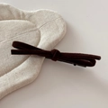 Close-up of deep brown velvet bow hair clip on a soft quilted beige linen background - Brown
