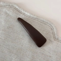 Gros plan sur une pince à cheveux triangulaire marron foncé à texture cuir grainé - Café Élégant - Pince Triangle Fine