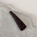 Détail macro d'une pince à cheveux triangulaire léopard sur tissu en lin beige - Léopard Élégant - Pince Triangle Fine