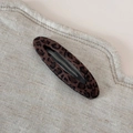 Détail du clip à cheveux léopard avec texture velours douce sur un fond beige en lin - Léopard Élégant - Barrette Ovale