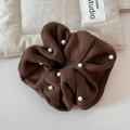 Detail of coffee brown knitted hair scrunchie with white pearls on a soft background - Coffee