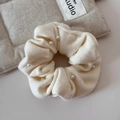 Detail view of a cream knit scrunchie with elegant faux pearl accents and soft fabric texture - Off-White