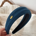 Dettaglio fascia in maglia a coste blu navy con emblema in metallo dorato e fodera nera - Cerchietto Twill con Etichetta Oro / Blu
