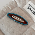 Close-up of tortoise shell hair clip with blue edges on a soft linen textured background - Blue Edged Leopard Hollow Oval