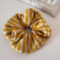 Makro-Detail eines elastischen Oversize-Scrunchie mit gelb-weißen Strickstreifen - Lazy Stil Wollschleife / Gelb
