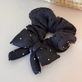 Detalle de coletero de punto negro con lazo de lunares blancos sobre fondo crema - Anillo De Lana De Punto - Lazo Negro