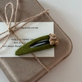 Detailed macro view of a forest green knit BB hair clip with a brown flocked bear and pearls - Green