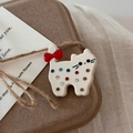 Detail of white acetate cat hair clip with colorful rhinestones and red bow on gift box - Off-white