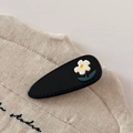 Close-up of black teardrop hair clip with white flower on rustic linen studio bag - Black