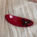 Detail of dark red acetate hair clip featuring a black bow and sparkling rhinestone - Red