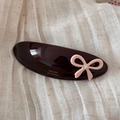 Close-up of brown acetate barrette with pink bow, shiny rhinestone and gold logo detail - Dark Coffee