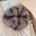 Close-up of soft coffee faux fur scrunchie on natural linen fabric background - Grey Brown